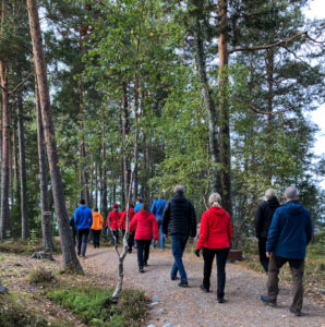 Ryhmä ihmisiä kävelee metsäpolkua.