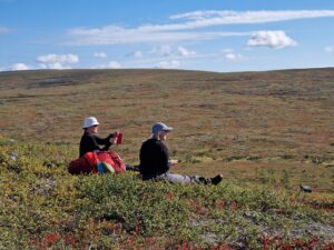 Ilona ja Ida istuvat maassa katsellen maisemia.