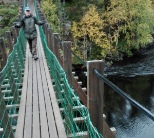 Mies kävelee riippusillalla kosken yläpuolella.